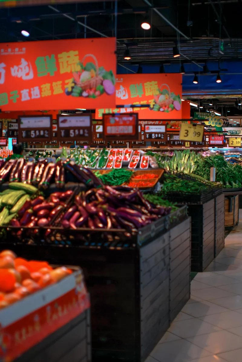 Colorful fresh produce aisle in an Asian supermarket with diverse vegetables on display.