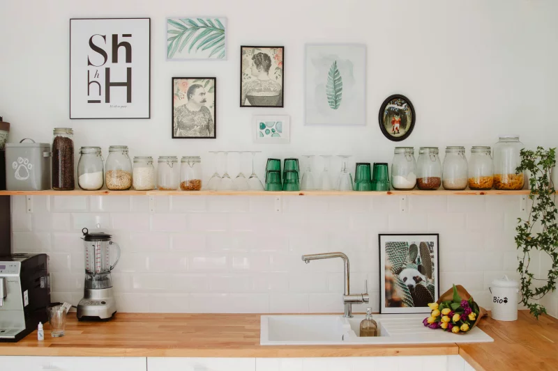 Contemporary kitchen in Estonia featuring wooden shelves, decor elements, and glass jars above a sink.