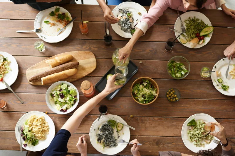 An overhead shot of a dining table featuring various pasta dishes and salads shared by a group.