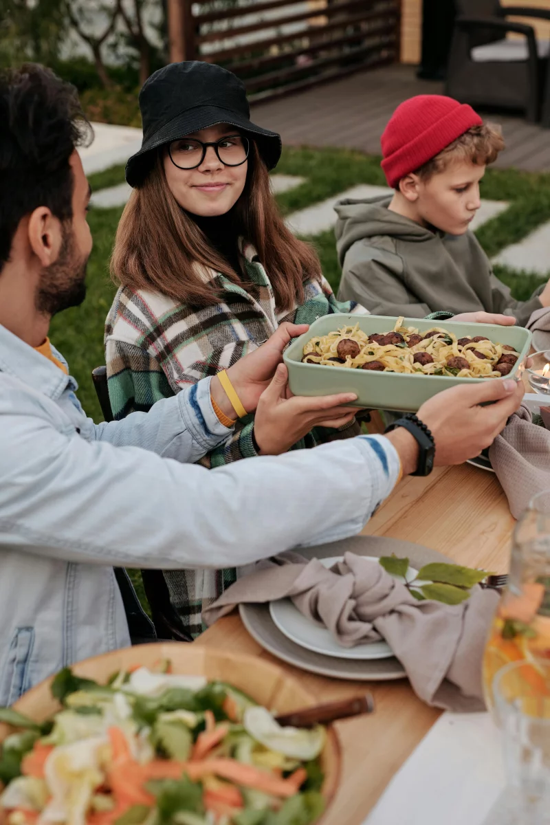 A joyful family gathering outdoors enjoying a summer picnic with food and smiles.