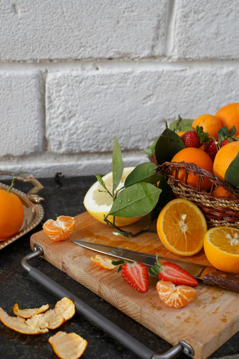 A vibrant still life of assorted fresh fruits including oranges and strawberries on a rustic cutting board.