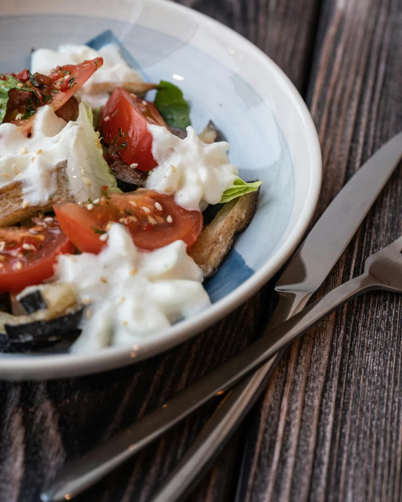 Delicious tomato and burrata salad with basil and a fork on a rustic table.