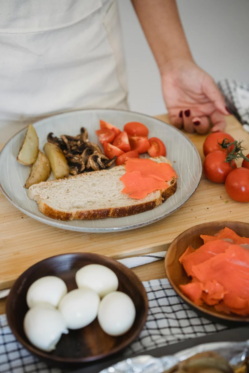 Appetizing breakfast plate featuring bread, salmon, mushrooms, tomatoes, and sliced potatoes.
