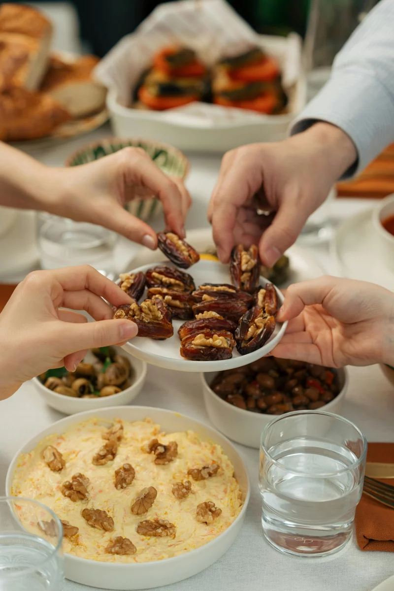 A group sharing dates and various dishes on a festive dining table, capturing warmth and togetherness.