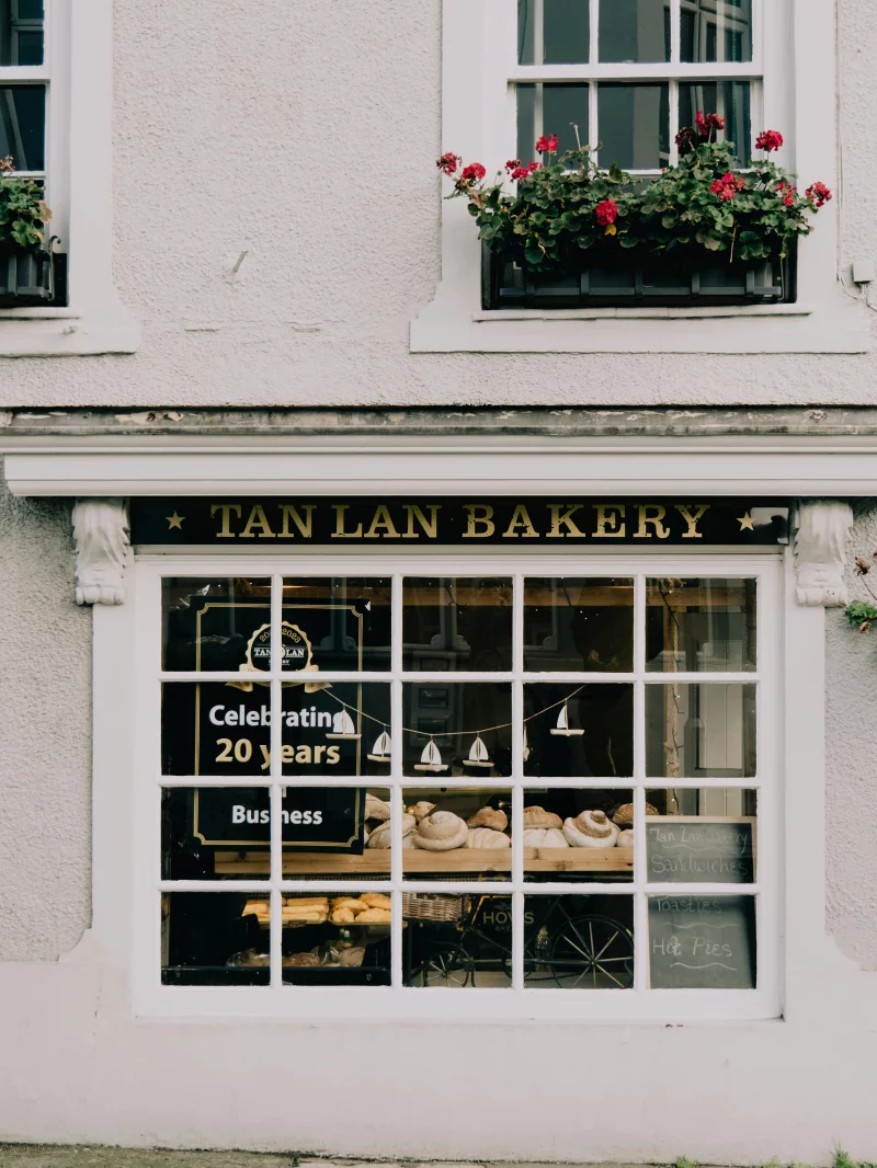 A quaint bakery storefront displaying fresh breads and anniversary signage in an urban area. Perfect city retail scene.