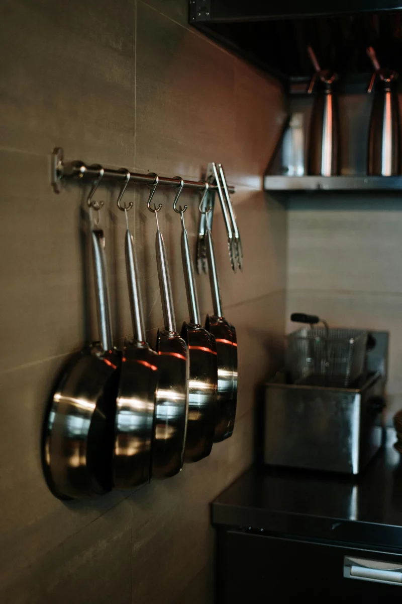 Elegant arrangement of stainless steel pans hanging in a contemporary kitchen setting.