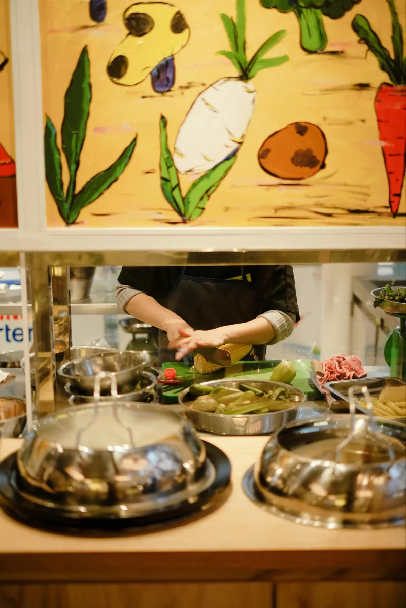 A chef chopping fresh vegetables in a vibrant kitchen setting with colorful decor.
