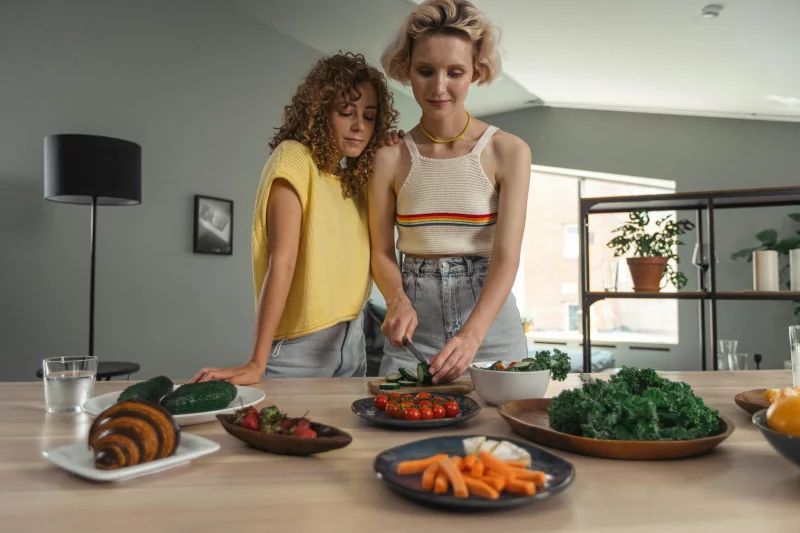 Couple cooking together in a modern kitchen, preparing a healthy meal with fresh vegetables, symbolizing a wholesome lifestyle.