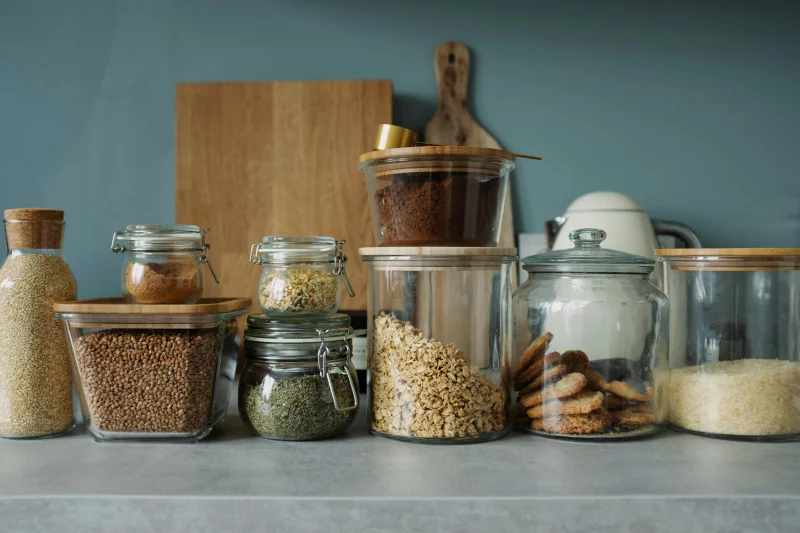 Neatly arranged glass jars with cookies, oats, spices, and ingredients on a kitchen counter.