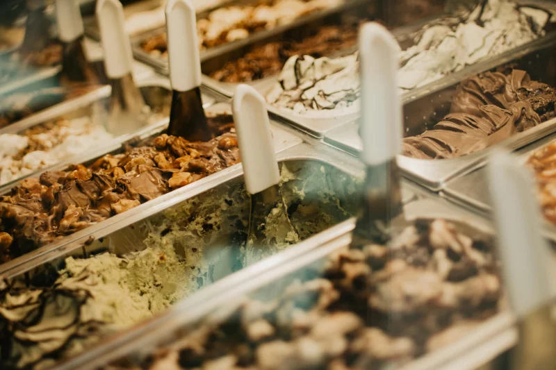 A vivid display of assorted gelato flavors in trays, showcasing rich textures and colors in a dessert store.