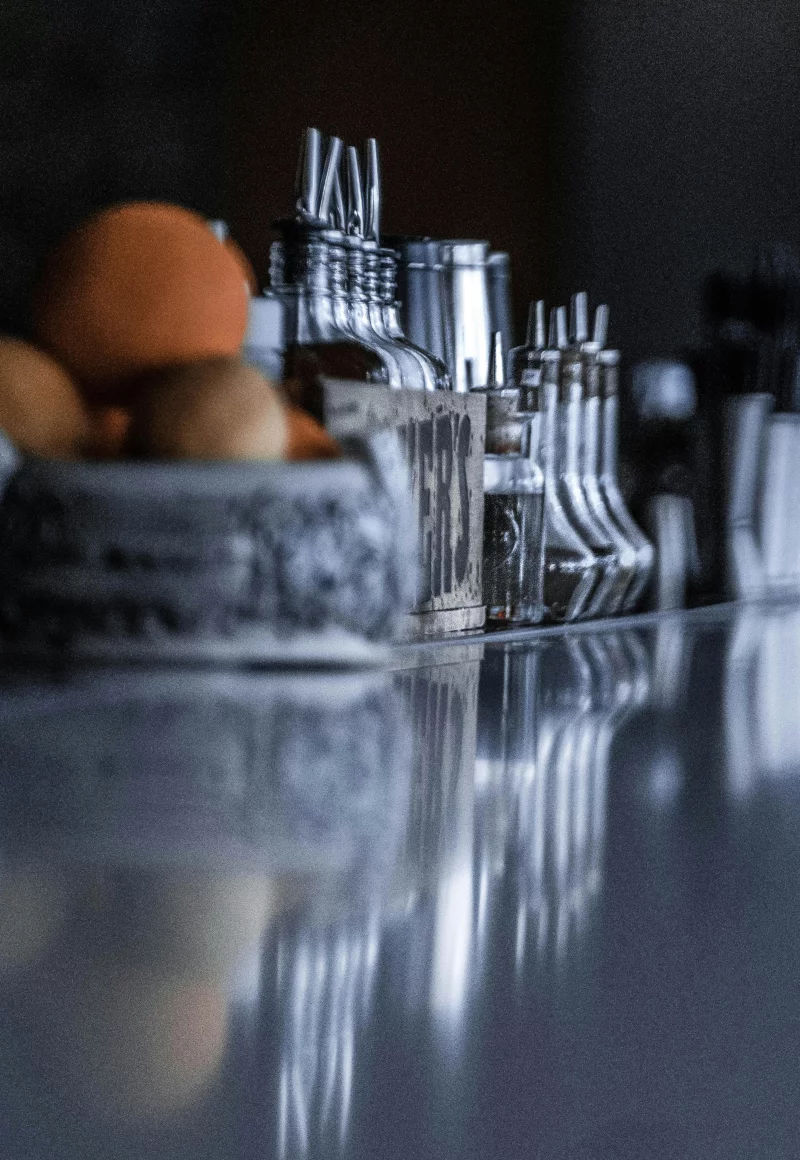 Stylish arrangement of glass jars, bottles, and oranges on a kitchen counter with reflections.