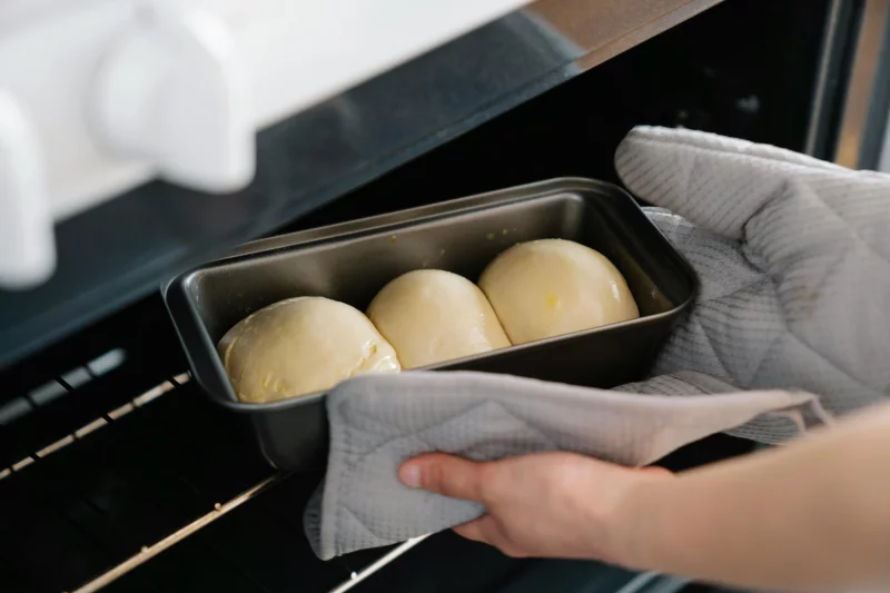 Close-up of a person placing homemade bread dough into an oven.
