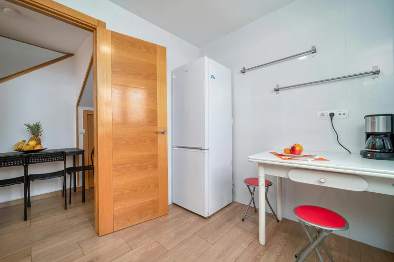 A modern kitchen featuring white appliances, wood elements, and a minimalist design.
