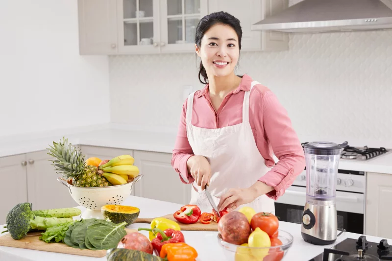 Woman slicing vegetables in kitchen, showcasing healthy living and cooking lifestyle.