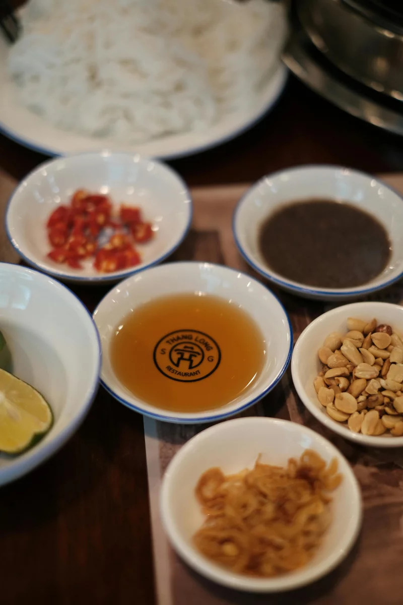 High-angle view of Vietnamese ingredients including peanuts, sauce, and chilies in bowls.