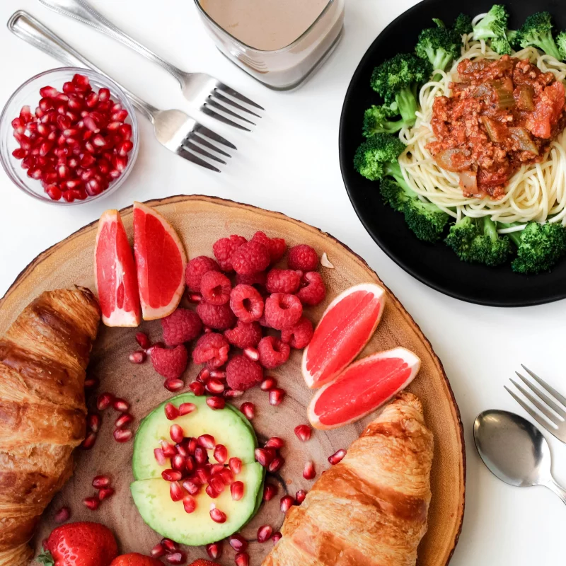 A vibrant breakfast spread with croissants, pasta, and fresh fruits, perfect for food lovers.