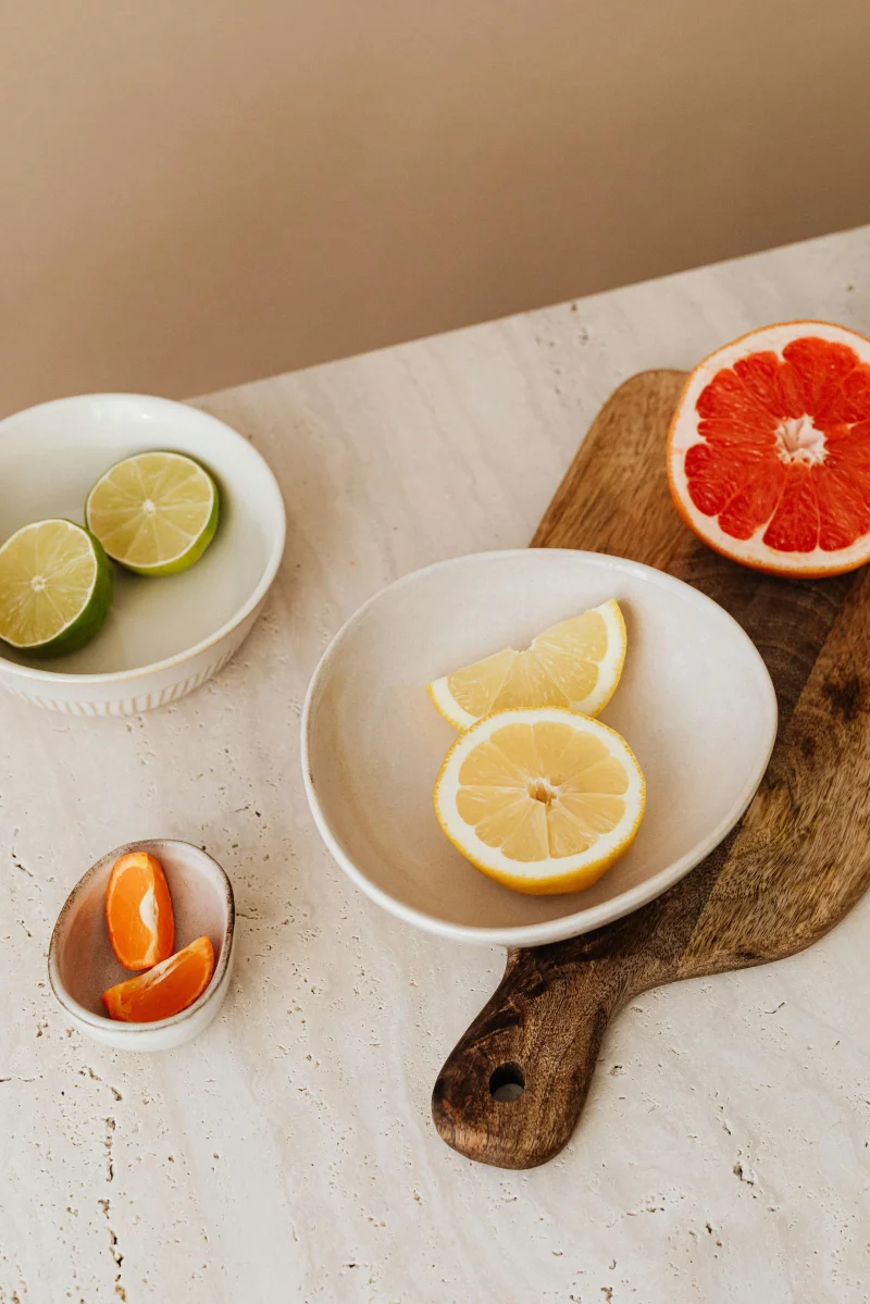Styled citrus fruits including lemons, limes, and grapefruit on marble and wood surfaces.