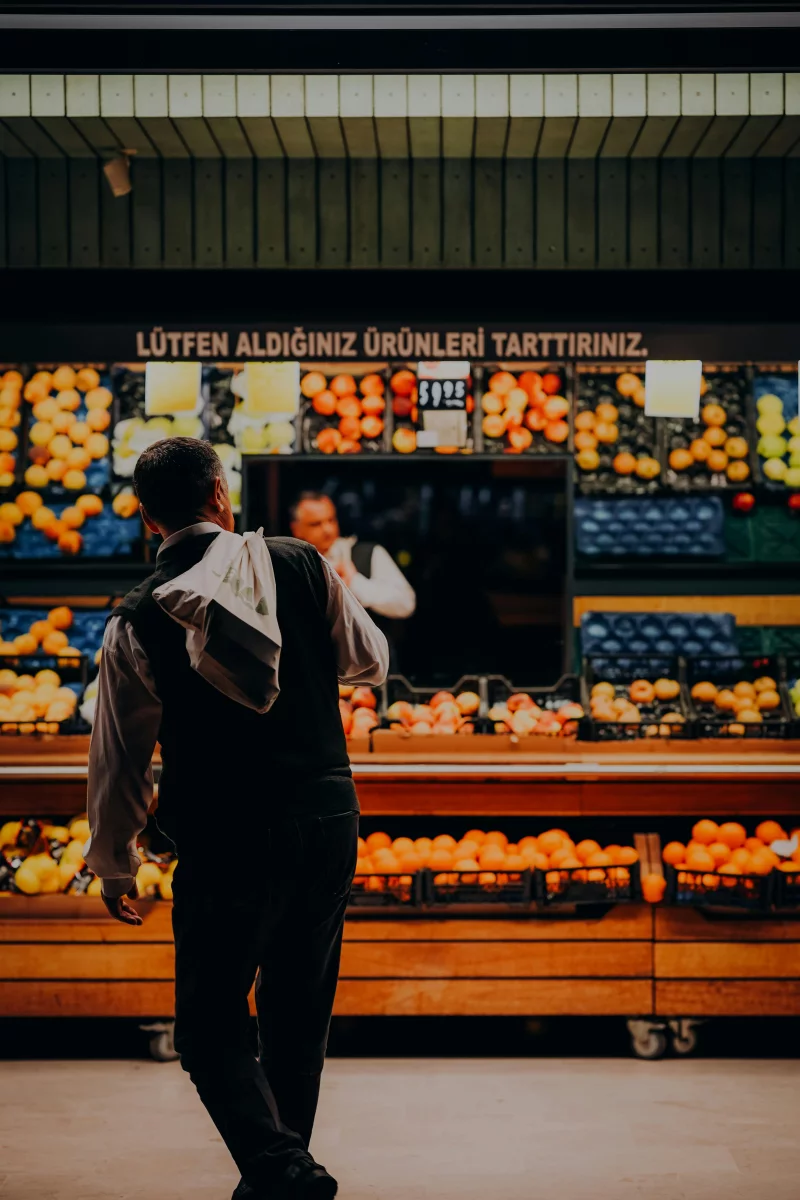 Man shopping in a vibrant fruit and vegetable market stall in Ankara, Türkiye.