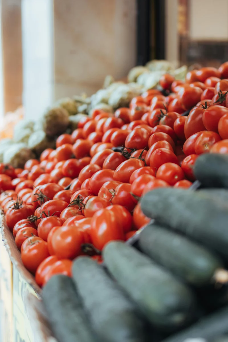 Vibrant tomatoes and cucumbers on display at a local market in Barcelona, Spain.