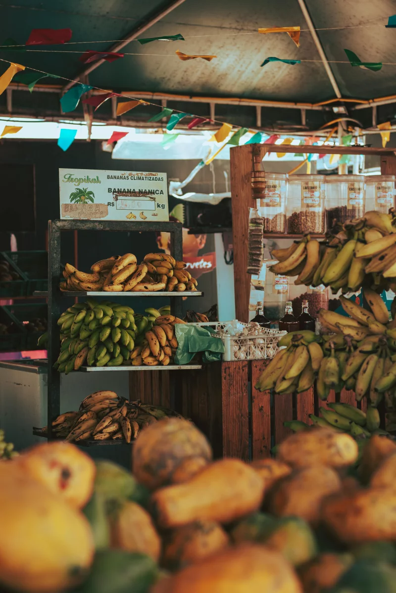 Colorful outdoor market stall displaying a variety of fresh bananas and papayas.