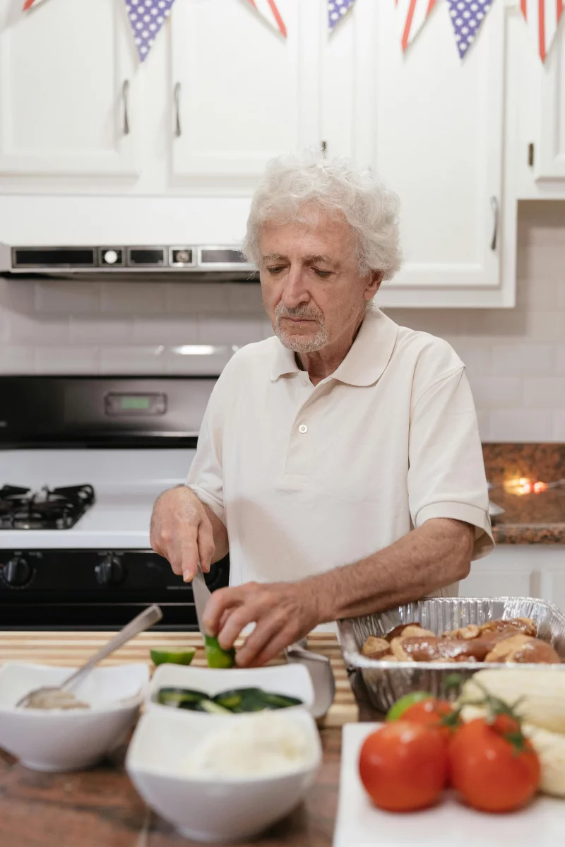 Senior man preparing vegetables at home kitchen counter for a meal.