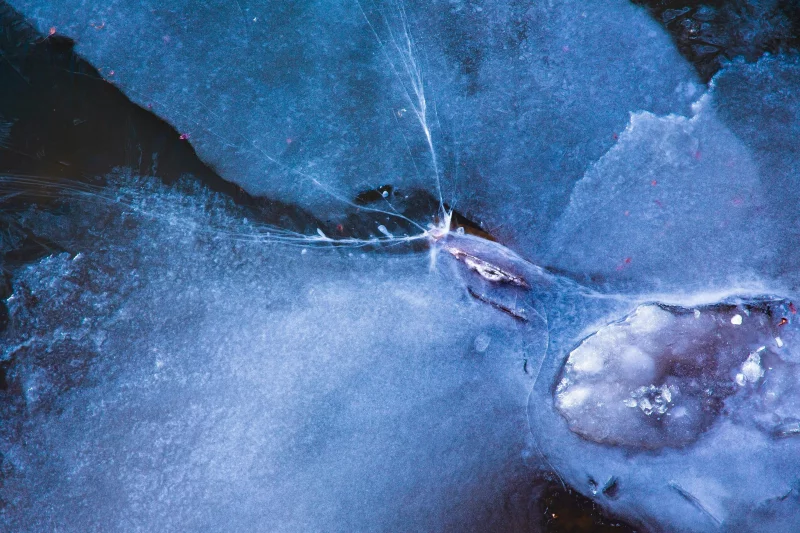 Full frame textured background of blue ice water with uneven bristly surface covered with cracks