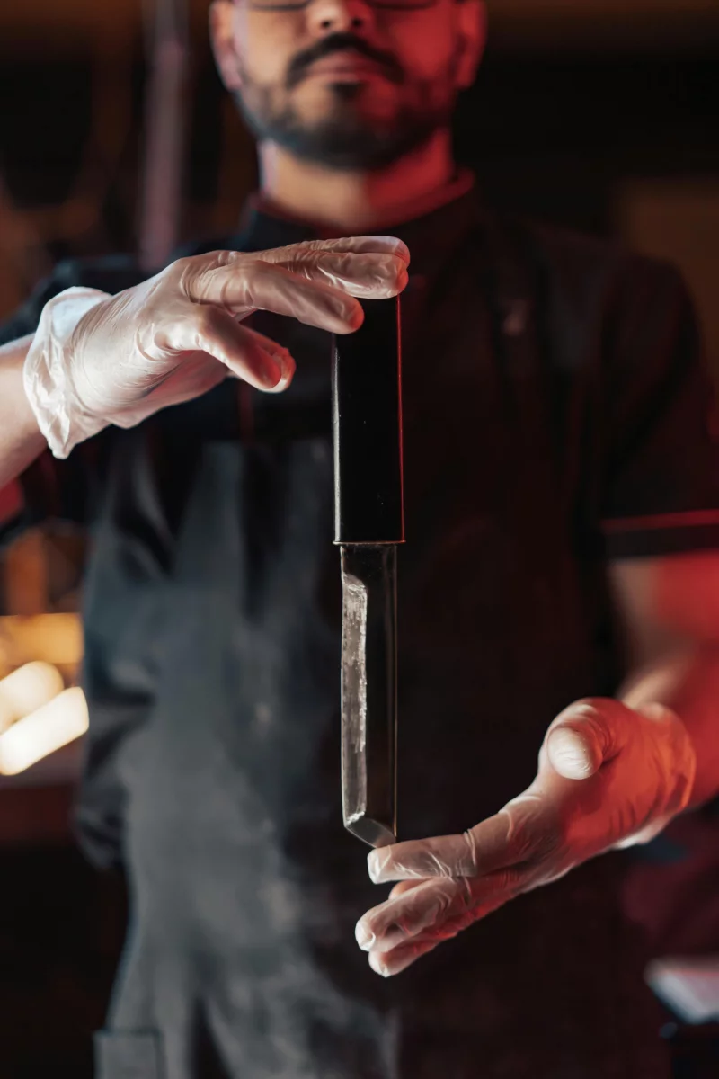 Close-up of a chef holding a knife with gloved hands, blurred background.