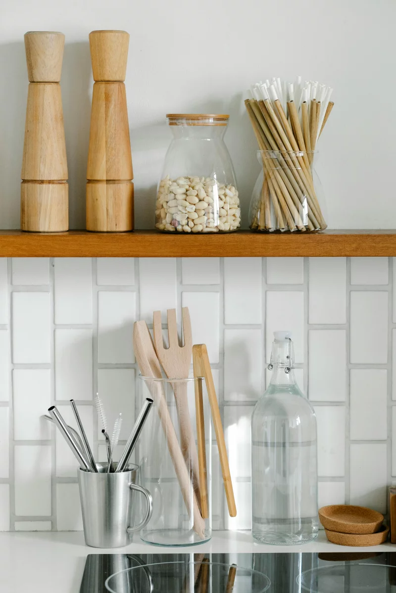 A well-organized kitchen shelf with wooden kitchenware, utensils, and storage jars.