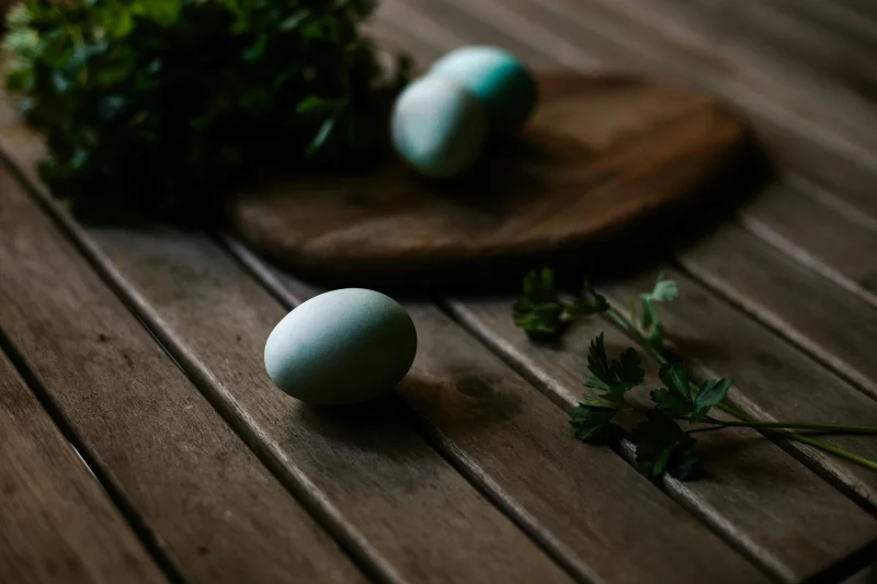 Organic blue eggs on a rustic wooden table with herbs, exuding a fresh, natural feel.
