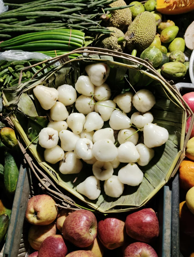 Assortment of fresh fruits including water apples at a vibrant market stand.