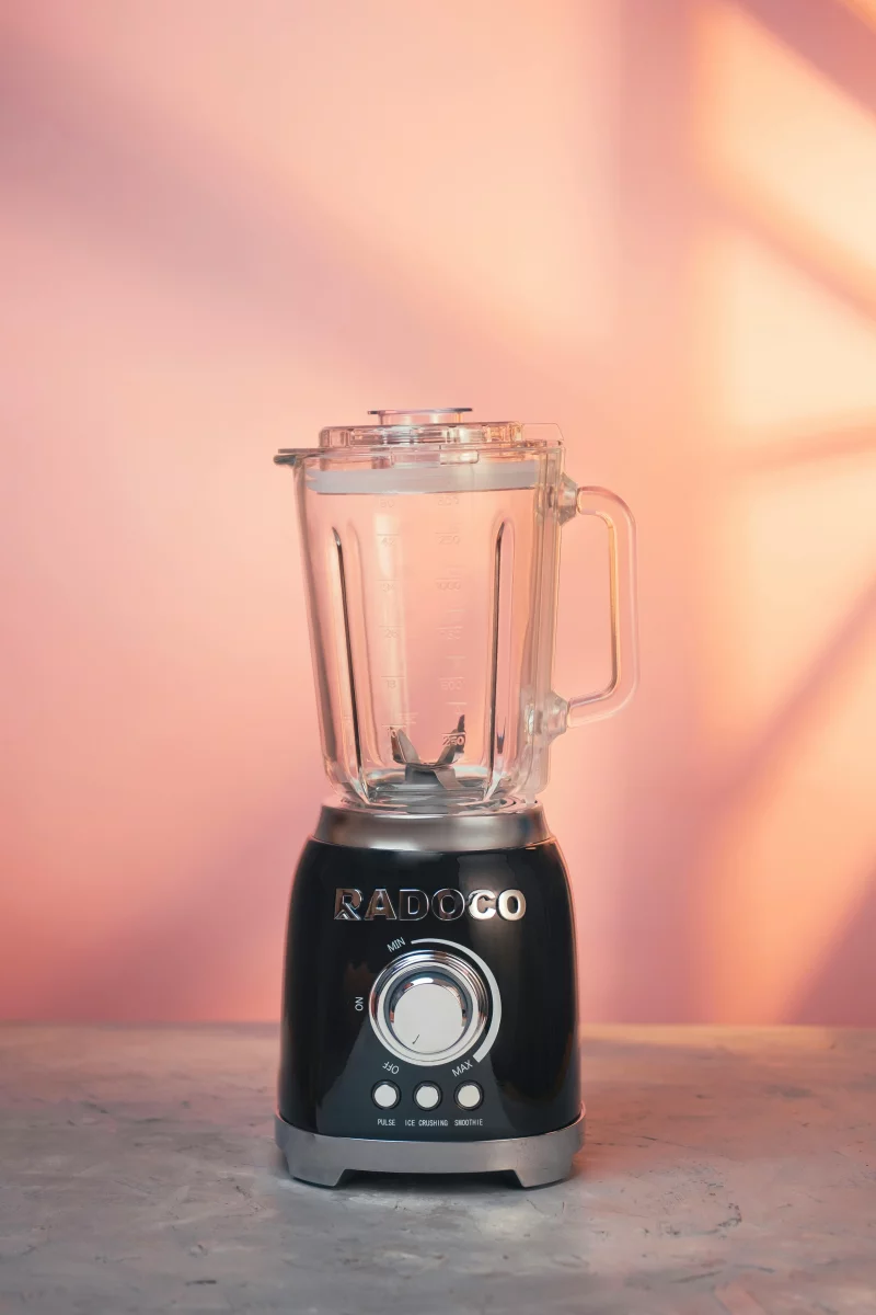 Black blender on a marble surface with a pink background, perfect for modern kitchens.