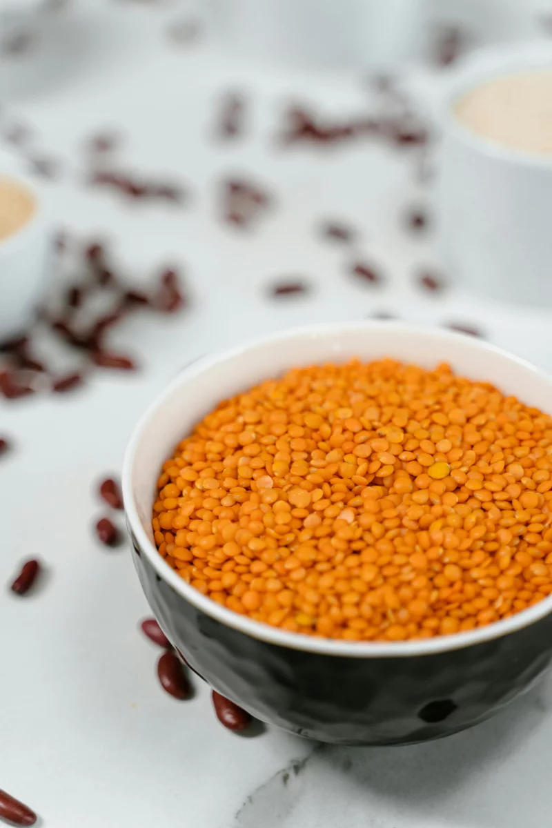 A close-up view of raw red lentils in a ceramic bowl on a kitchen counter.