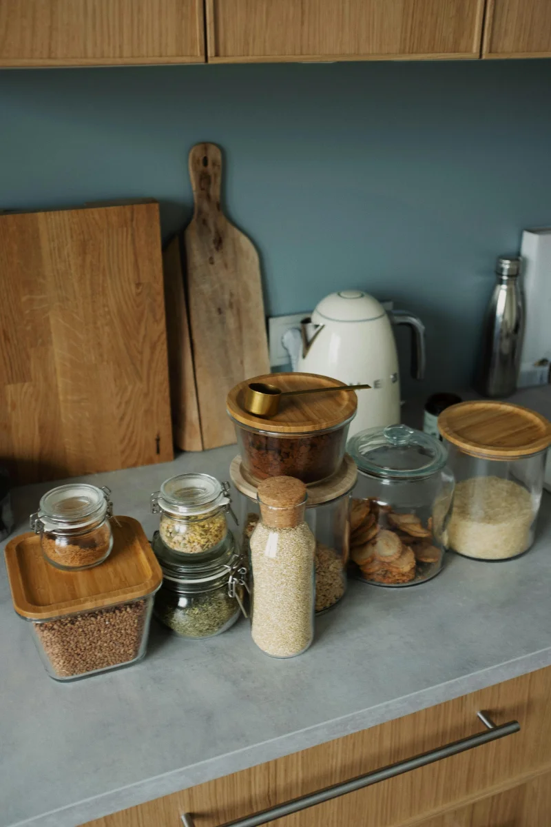 Stylish kitchen setup with glass jars, wooden chopping boards, and minimalistic decor on a countertop.