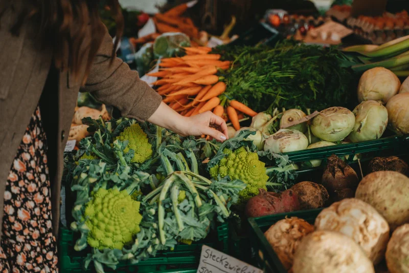 Woman selecting fresh vegetables at a vibrant local farmers market.