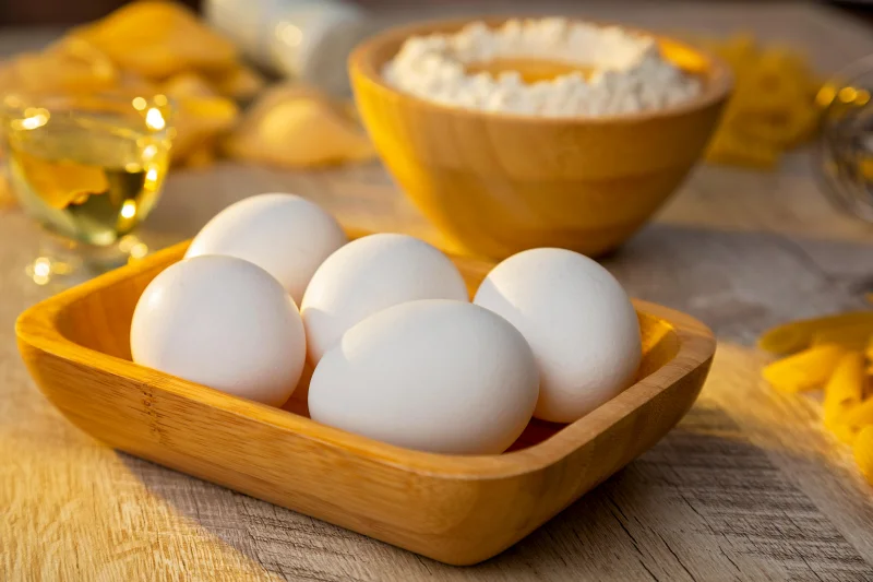 A warm, rustic photo featuring eggs and flour in a wooden setting, ideal for baking themes.