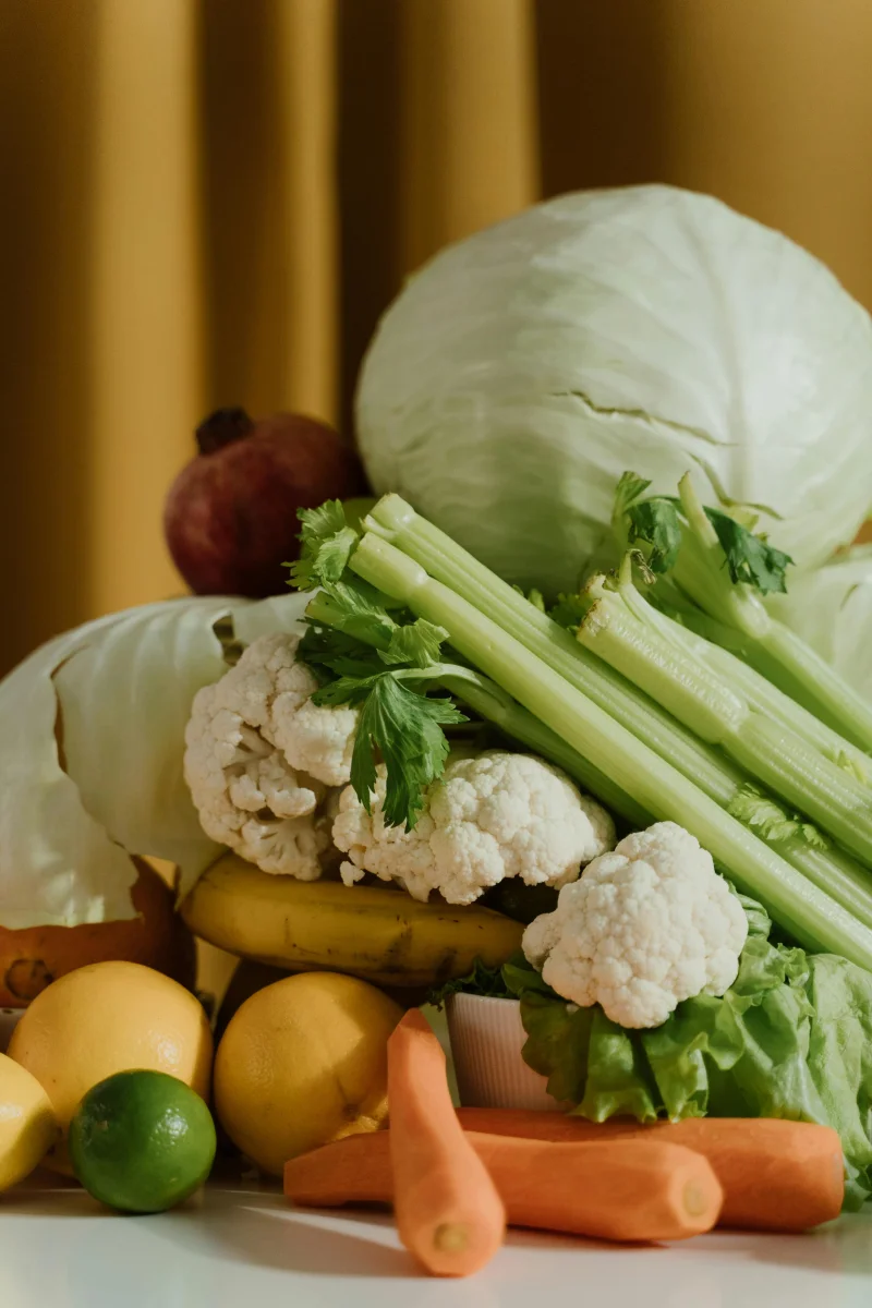 A vibrant assortment of fresh organic vegetables and fruits including cabbage, celery, and lemons.