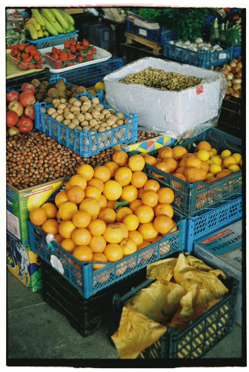 Colorful variety of fresh fruits in a market, showcasing oranges, nuts, and more in crates.