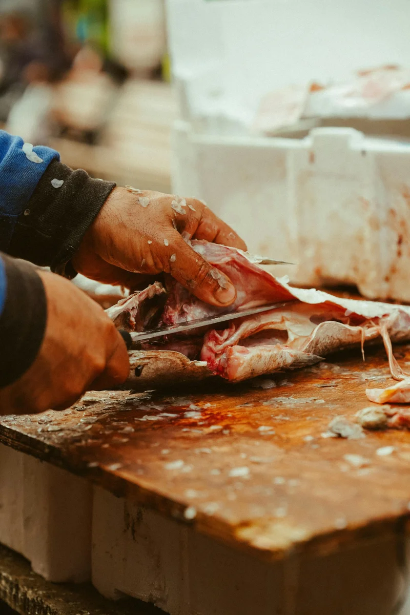 Fish being expertly prepared on a wooden board in Ankara's bustling market.