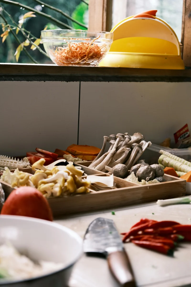 A colorful arrangement of fresh vegetables and mushrooms on a kitchen countertop, ready for cooking.