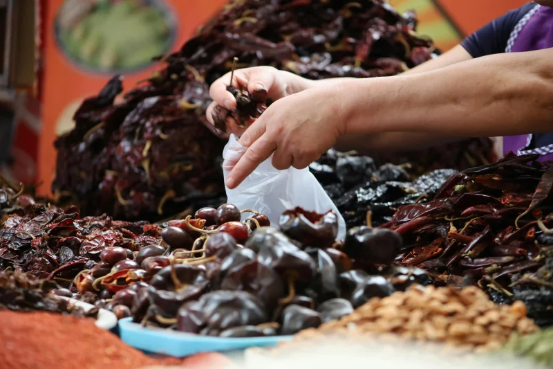 Close-up of hands choosing dried peppers, vibrant market atmosphere.