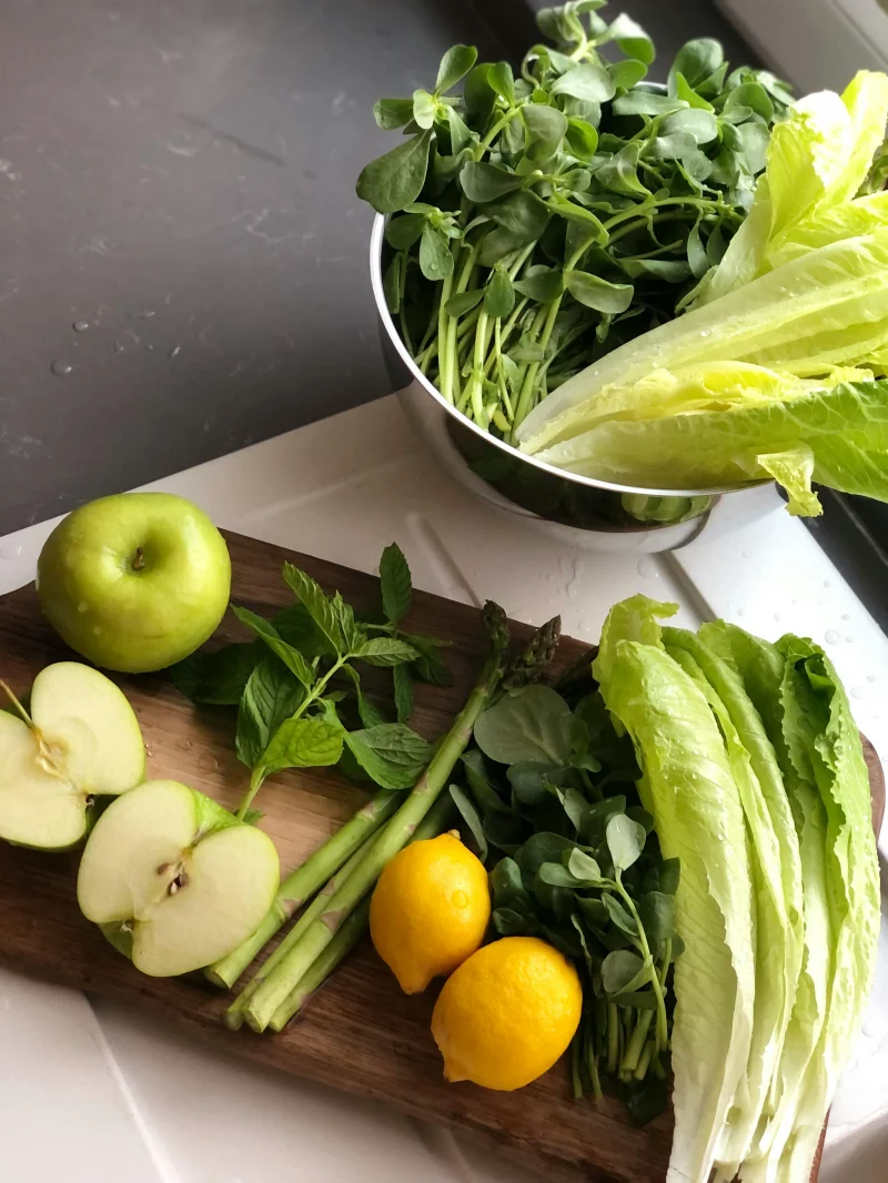 Assorted green vegetables and fruits on a kitchen counter, perfect for healthy eating.