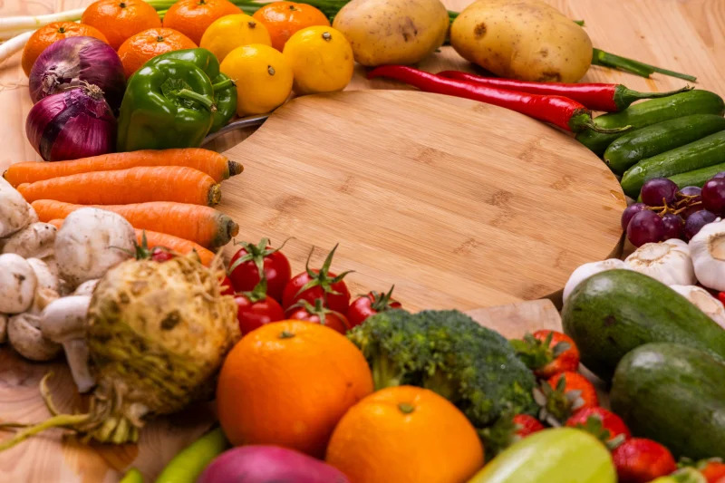 Vibrant variety of fresh fruits and vegetables on a wooden table for healthy eating.