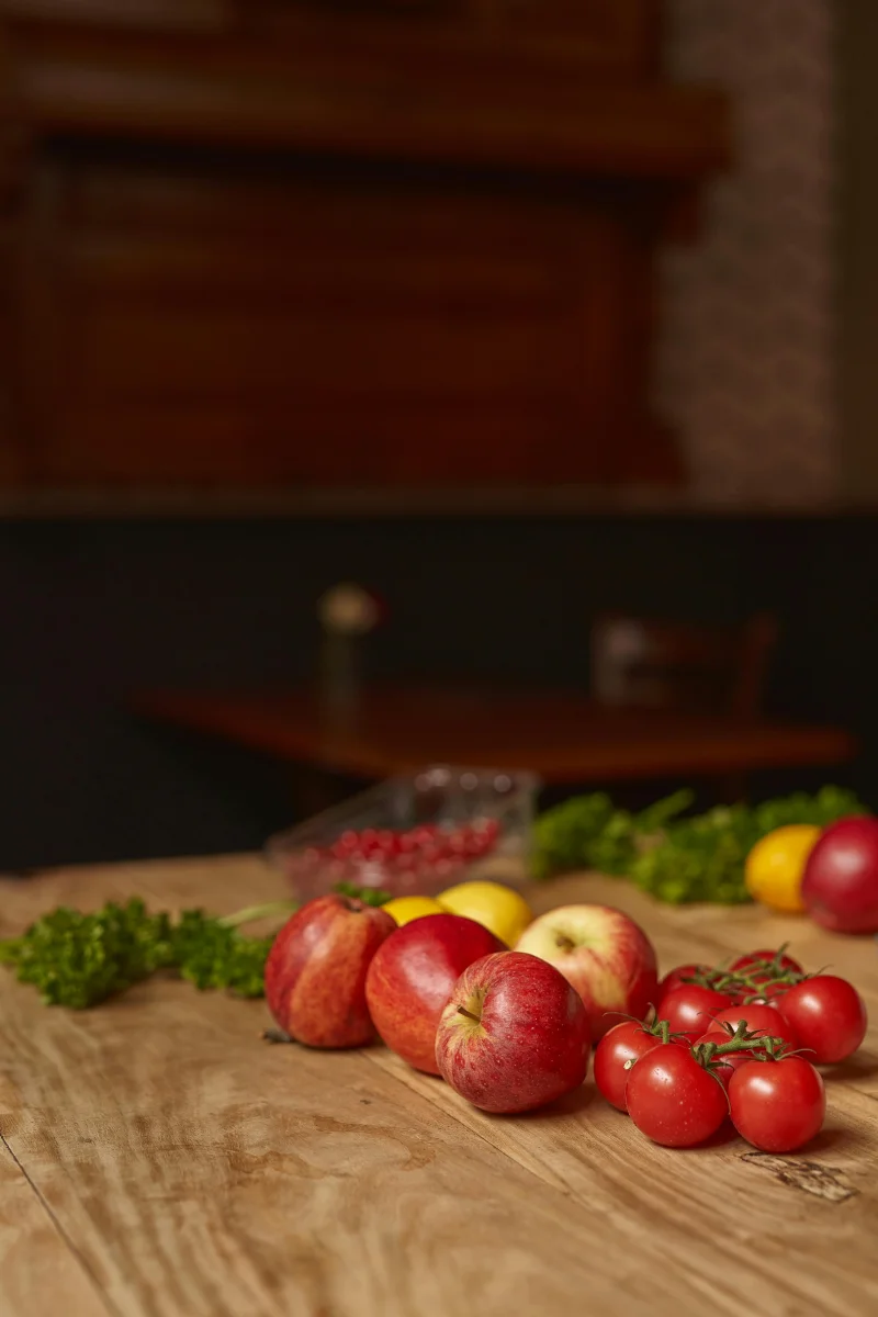 A variety of fresh fruits and vegetables on a rustic kitchen table, showcasing healthy eating.