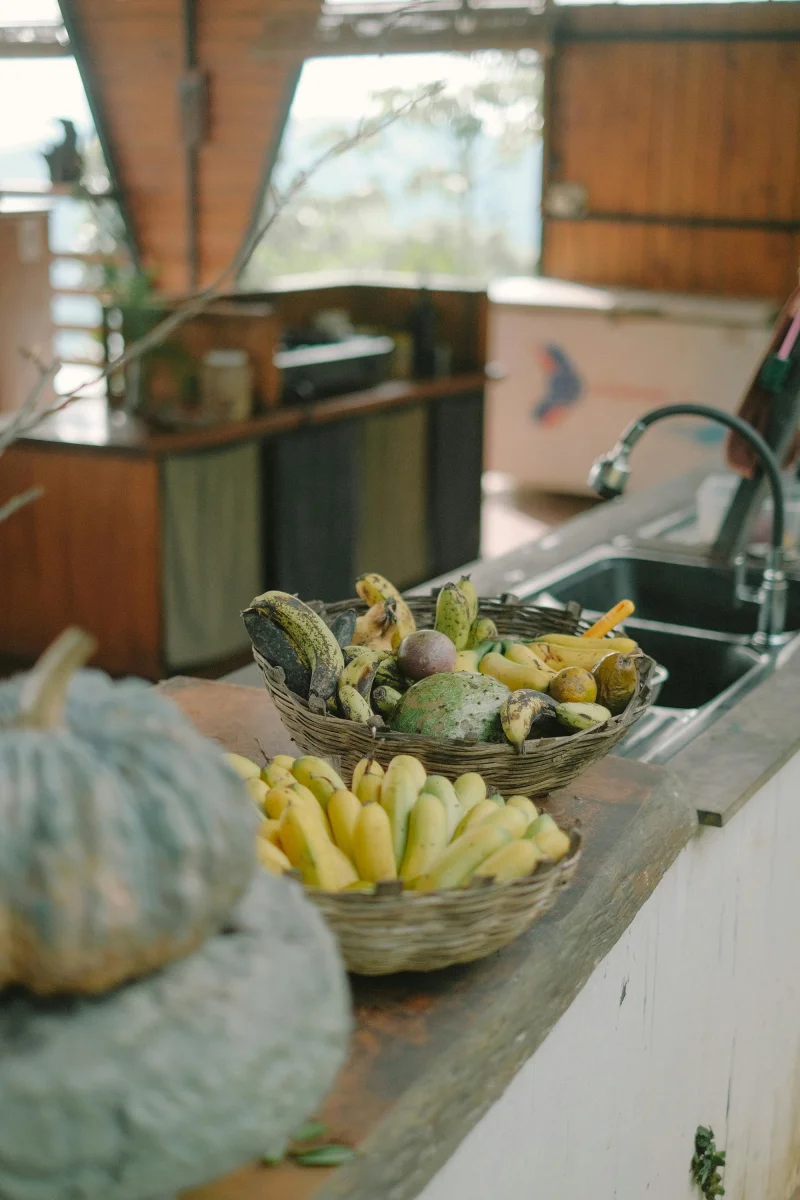 A rustic kitchen setup with baskets of fresh fruits and vegetables on a wooden counter.