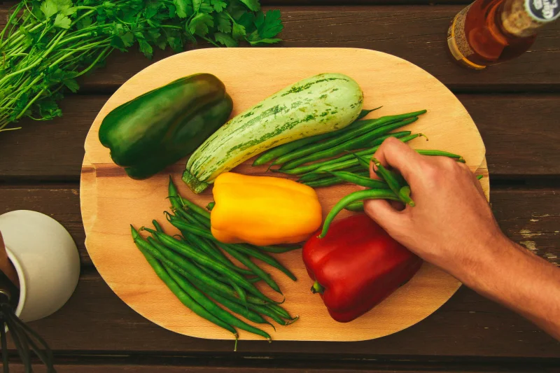 Colorful mix of fresh vegetables on a cutting board outdoors.