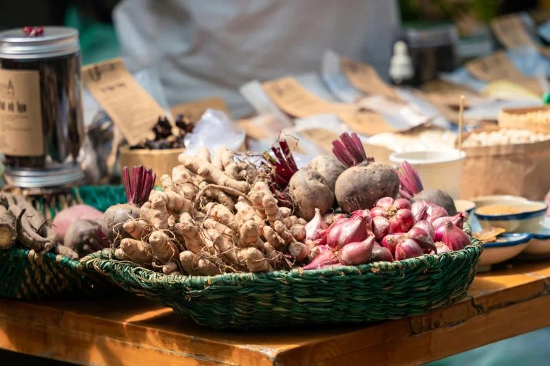 A colorful assortment of root vegetables and spices on display in an outdoor market setting.