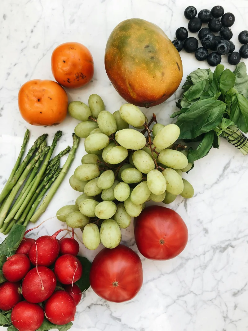A vibrant flat lay of fresh fruits and vegetables on a marble surface, showcasing healthy food options.