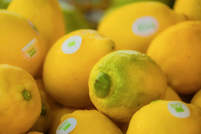 A close-up of fresh organic lemons adorned with bio stickers in vibrant yellow hues.