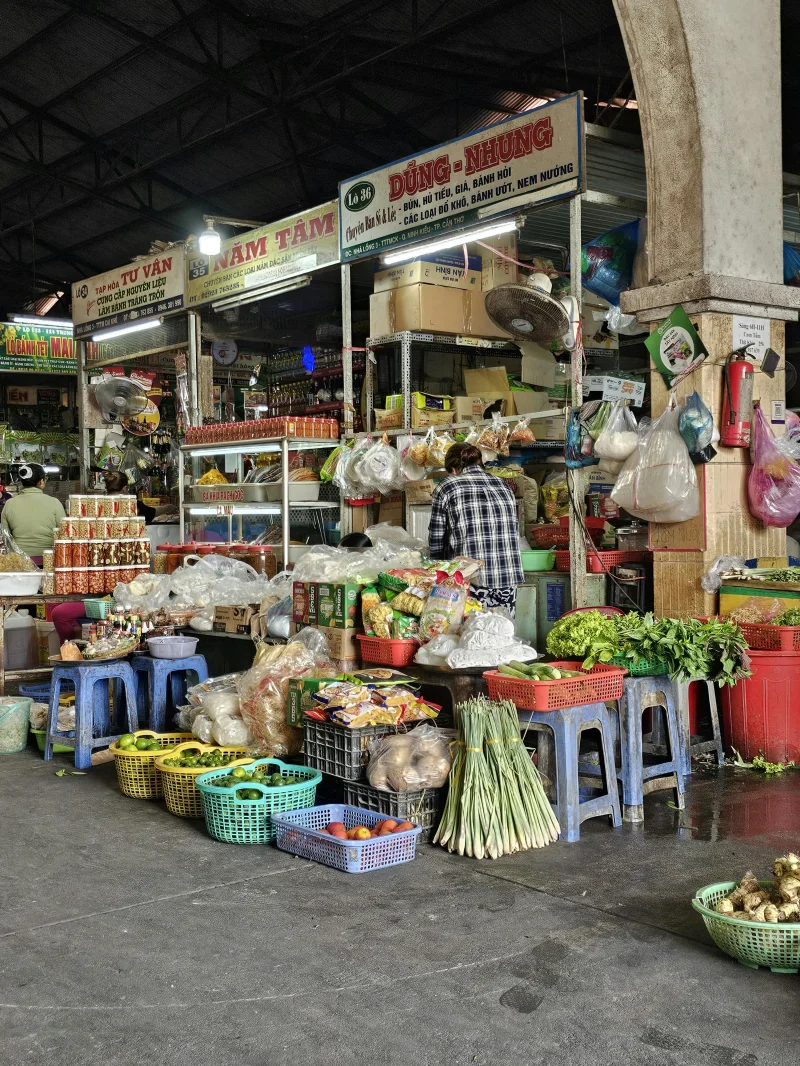 Colorful market stall in Vietnam showcasing fresh produce and local foods in a lively indoor setting.