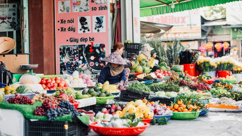 Colorful street market scene in Vietnam featuring a variety of fresh fruits and vegetables.